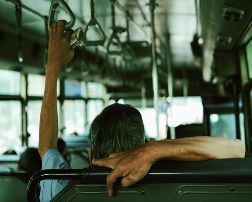 Person holding a smartphone while commuting on a public bus